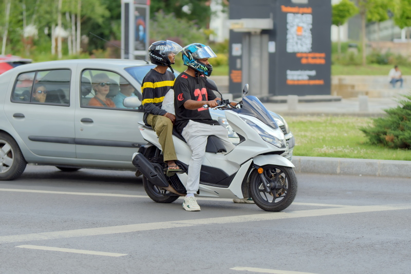 26 - Two persons on a white Honda PCX scooter featuring a stepped-up passenger seat and a modern, angular design